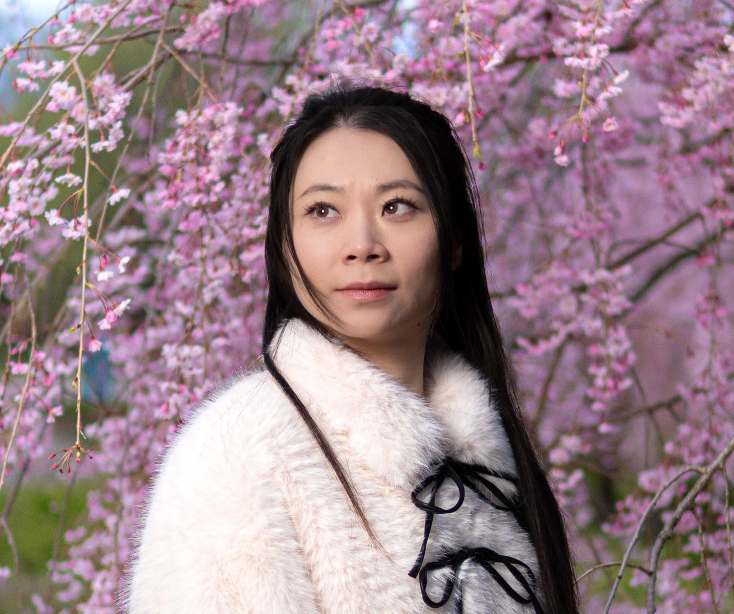 Environmental portrait of a woman among cherry blossoms